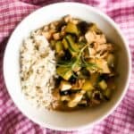 A bowl of Quick Rosemary Lemon Chicken Stew with rice on a pink and white checkered kitchen towel